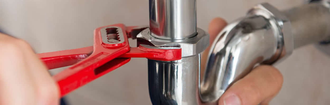 Plumber Using Wrench To Fix Sink Pipes